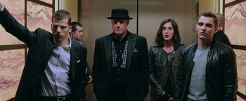 Movie still from “Now You See Me 2” (2016), directed by Jon M. Chu – A man in a suit and a hat standing next to a woman in an elevator; Medium shot, Low angle