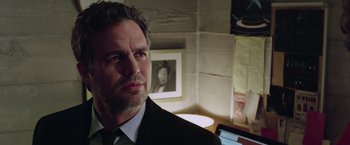 Movie still from “Now You See Me 2” (2016), directed by Jon M. Chu – A man wearing a suit and tie in front of a picture; Close Up shot, Low angle