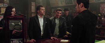 Movie still from “Now You See Me 2” (2016), directed by Jon M. Chu – A group of men standing around a table; Medium shot, Over the shoulder angle