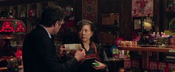 Movie still from “Now You See Me 2” (2016), directed by Jon M. Chu – An older woman holding a piece of paper in front of a younger man; Medium shot, Over the shoulder angle