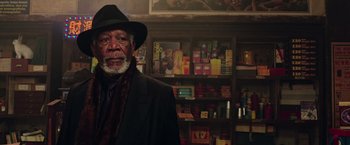 Movie still from “Now You See Me 2” (2016), directed by Jon M. Chu – An older man standing in front of shelves filled with cigarettes; Medium shot, Low angle