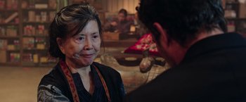 Movie still from “Now You See Me 2” (2016), directed by Jon M. Chu – An older woman smiling at the camera while a younger man looks at her; Close Up shot, Over the shoulder angle