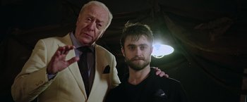 Movie still from “Now You See Me 2” (2016), directed by Jon M. Chu – A man standing next to an older man in front of a light; Medium shot, Over the shoulder angle