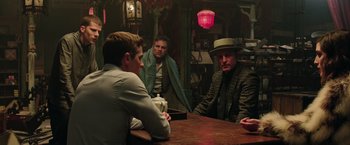 Movie still from “Now You See Me 2” (2016), directed by Jon M. Chu – A group of men sitting at a table in a room; Medium shot, Over the shoulder angle