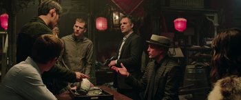 Movie still from “Now You See Me 2” (2016), directed by Jon M. Chu – A group of men standing around a table talking; Medium shot, Low angle
