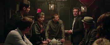 Movie still from “Now You See Me 2” (2016), directed by Jon M. Chu – A group of people standing around a table; Medium shot, Over the shoulder angle