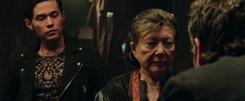 Movie still from “Now You See Me 2” (2016), directed by Jon M. Chu – An older woman wearing a leather jacket; Close Up shot, Over the shoulder angle