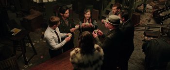 Movie still from “Now You See Me 2” (2016), directed by Jon M. Chu – A group of people sitting at a table with food in front of them; Medium shot, High angle