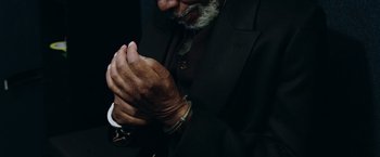 Movie still from “Now You See Me 2” (2016), directed by Jon M. Chu – An older man in a black suit clasps his hands; Extreme Close Up shot, High angle