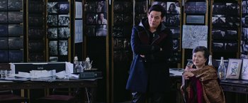 Movie still from “Now You See Me 2” (2016), directed by Jon M. Chu – A man standing in front of a wall of pictures; Medium shot, Over the shoulder angle