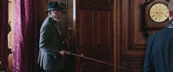 Movie still from “Now You See Me 2” (2016), directed by Jon M. Chu – An older man in a suit and hat holding a cane; Medium shot, Over the shoulder angle