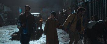 Movie still from “Nowhere” (2023), directed by Albert Pintó – A woman walking down a street holding the hand of a man; Medium shot, Over the shoulder angle