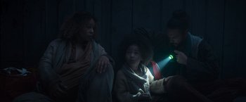 Movie still from “Nowhere” (2023), directed by Albert Pintó – A group of people sitting in a dark room; Medium shot, High angle
