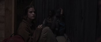 Movie still from “Nowhere” (2023), directed by Albert Pintó – A woman sitting on the ground in a dark room; Medium shot, Over the shoulder angle