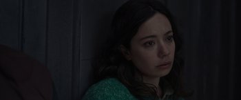 Movie still from “Nowhere” (2023), directed by Albert Pintó – A young woman is looking at the camera while standing in a dark room; Close Up shot, High angle