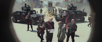 Movie still from “Nowhere” (2023), directed by Albert Pintó – A group of men standing next to each other on a street; Wide shot, Over the shoulder angle