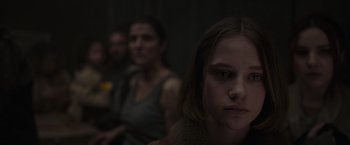 Movie still from “Nowhere” (2023), directed by Albert Pintó – A young girl looking sad in front of a group of people; Close Up shot, Over the shoulder angle