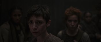 Movie still from “Nowhere” (2023), directed by Albert Pintó – A woman with short dark hair is looking at the camera; Close Up shot, Over the shoulder angle
