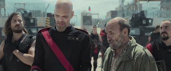 Movie still from “Nowhere” (2023), directed by Albert Pintó – Two bald men standing next to each other on the street; Medium shot, Over the shoulder angle