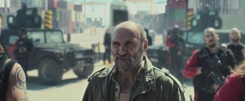 Movie still from “Nowhere” (2023), directed by Albert Pintó – An old man with a beard and a mustache is standing in the middle of the street; Medium shot, Over the shoulder angle
