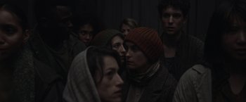 Movie still from “Nowhere” (2023), directed by Albert Pintó – A group of people standing in a dark room; Close Up shot, Over the shoulder angle