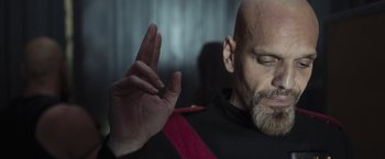 Movie still from “Nowhere” (2023), directed by Albert Pintó – A man with a shaved head and a red neck tie; Close Up shot, Low angle