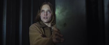 Movie still from “Nowhere” (2023), directed by Albert Pintó – A woman in a brown robe holding a metal object; Close Up shot, Low angle