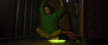 Movie still from “Nowhere” (2023), directed by Albert Pintó – A woman sitting on the ground with her arms raised; Medium shot, High angle