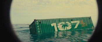 Movie still from “Nowhere” (2023), directed by Albert Pintó – A large green container ship in the water; Extreme Wide shot, Overhead angle
