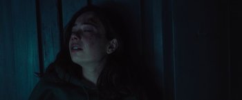 Movie still from “Nowhere” (2023), directed by Albert Pintó – A woman with a bruised face is laying in a dark room; Close Up shot, Over the shoulder angle