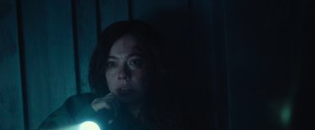 Movie still from “Nowhere” (2023), directed by Albert Pintó – A woman is looking at the camera in a dark room; Close Up shot, Over the shoulder angle