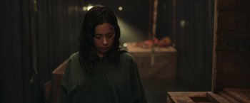 Movie still from “Nowhere” (2023), directed by Albert Pintó – A woman with a bruised face standing in a dark room; Medium shot, Over the shoulder angle