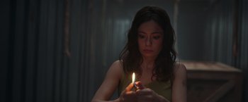 Movie still from “Nowhere” (2023), directed by Albert Pintó – A woman is holding a lit candle in a dark room; Close Up shot, Low angle