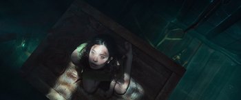 Movie still from “Nowhere” (2023), directed by Albert Pintó – A woman is sitting on the ground in a dark room; Medium shot, Overhead angle