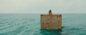 Movie still from “Nowhere” (2023), directed by Albert Pintó – A person standing on top of a box in the middle of the ocean; Extreme Wide shot, High angle