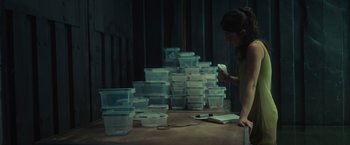 Movie still from “Nowhere” (2023), directed by Albert Pintó – A woman standing in front of a pile of plastic food containers; Medium shot, Low angle