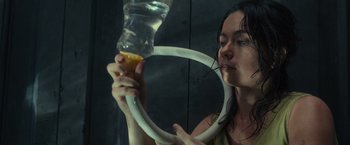 Movie still from “Nowhere” (2023), directed by Albert Pintó – A woman is holding a water bottle with a tube attached to it; Close Up shot, Low angle
