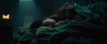 Movie still from “Nowhere” (2023), directed by Albert Pintó – A young boy laying in a bed under a green blanket; Close Up shot, High angle
