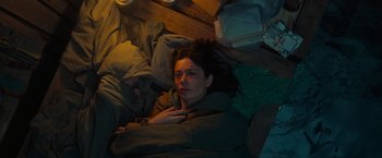 Movie still from “Nowhere” (2023), directed by Albert Pintó – A woman laying in a bed with many items; Medium shot, High angle