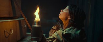 Movie still from “Nowhere” (2023), directed by Albert Pintó – A woman holding a lit candle in her hands; Close Up shot, Low angle