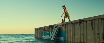 Movie still from “Nowhere” (2023), directed by Albert Pintó – A woman standing on the side of a pier near the water; Extreme Wide shot, Low angle