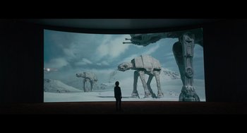 Movie still from “Obi-Wan Kenobi: A Jedi's Return” (2022), directed by David Gelb – A man standing in front of a screen with a picture of star wars; Wide shot, Low angle