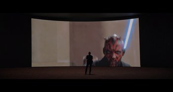 Movie still from “Obi-Wan Kenobi: A Jedi's Return” (2022), directed by David Gelb – A man standing in front of a screen with a darth maul image projected on it; Wide shot, Over the shoulder angle