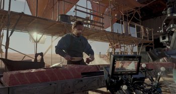 Movie still from “Obi-Wan Kenobi: A Jedi's Return” (2022), directed by David Gelb – A man is cooking meat on a grill in a construction site; Wide shot, Over the shoulder angle