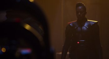 Movie still from “Obi-Wan Kenobi: A Jedi's Return” (2022), directed by David Gelb – A man in a black outfit standing in a dark room; Medium shot, Over the shoulder angle