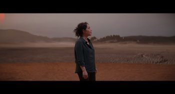 Movie still from “Obi-Wan Kenobi: A Jedi's Return” (2022), directed by David Gelb – A woman standing on a dirt field looking up at the sky; Wide shot, High angle
