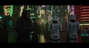 Movie still from “Obi-Wan Kenobi: A Jedi's Return” (2022), directed by David Gelb – A group of people standing in a city at night; Wide shot, Over the shoulder angle
