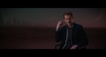 Movie still from “Obi-Wan Kenobi: A Jedi's Return” (2022), directed by David Gelb – A man sitting in a chair in front of a city skyline; Medium shot, Over the shoulder angle