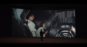Movie still from “Obi-Wan Kenobi: A Jedi's Return” (2022), directed by David Gelb – A man standing in front of a large screen; Wide shot, Low angle
