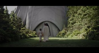 Movie still from “Obi-Wan Kenobi: A Jedi's Return” (2022), directed by David Gelb – A man and a child walking in front of a building; Extreme Wide shot, Low angle